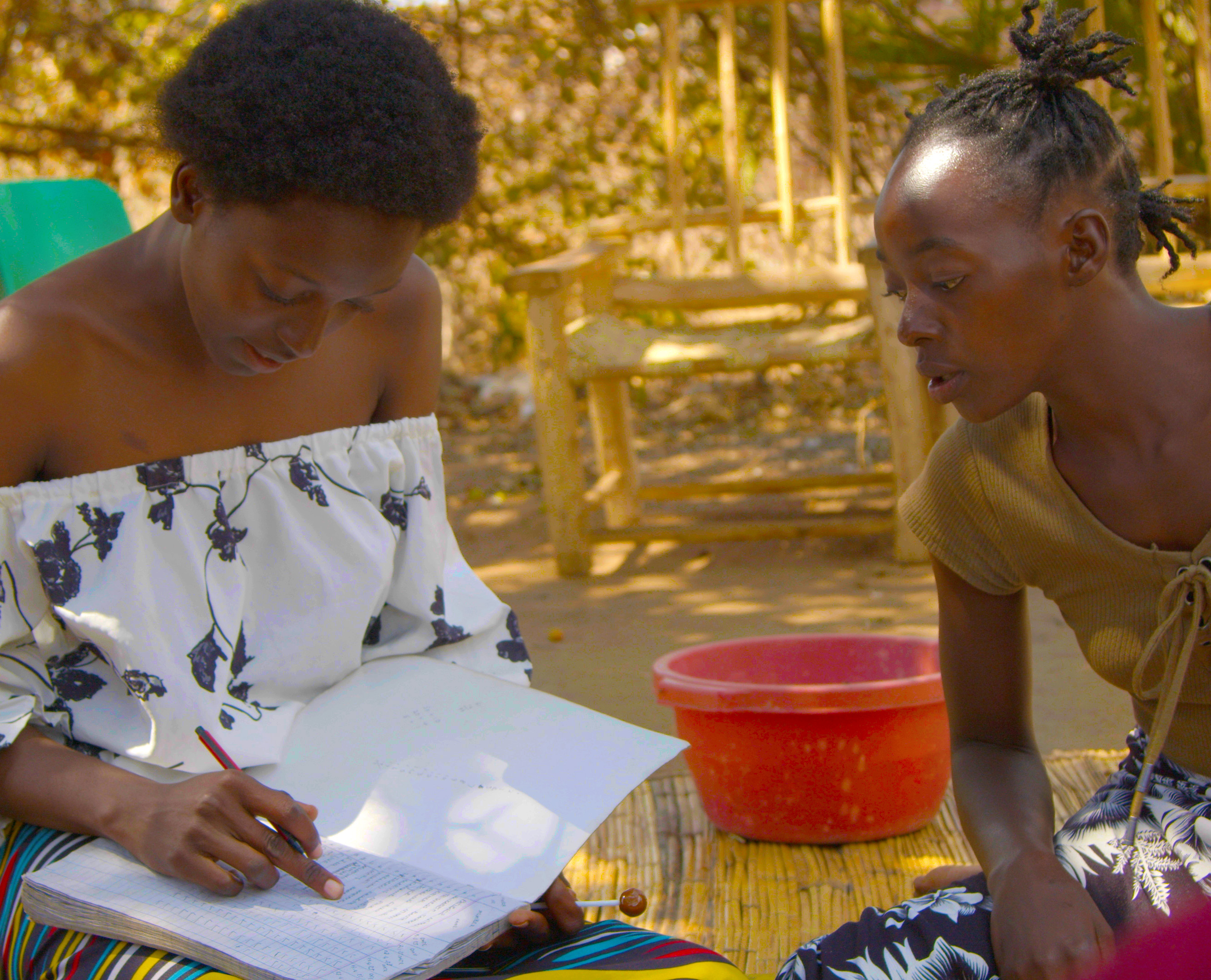 Two women work in a dossier at a Savings group with CARE Canada. Photo credit: Ufulu Studio creator, CARE Canada, Fairpicture.